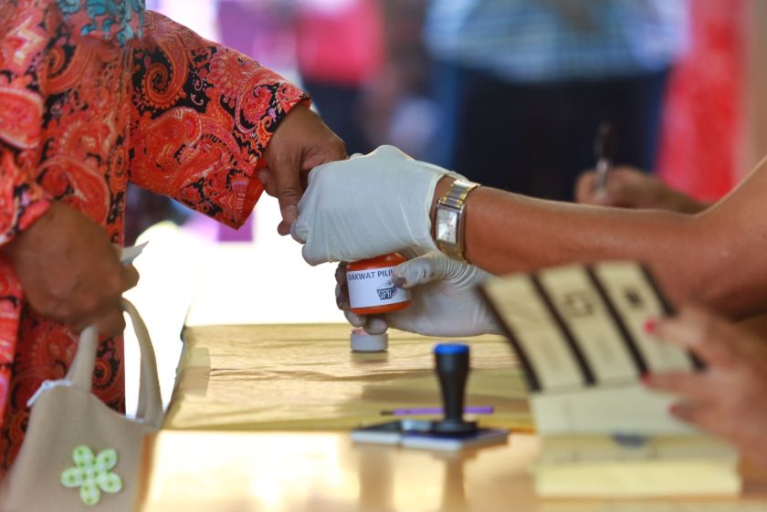 Malay Mail An election clerk dipping the finger of a voter in indelible ink.